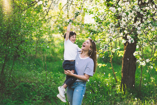 Счастливого Дня Матери. Мать с маленьким сыном в весеннем саду в золотой час. Мама и сын - Фото, изображение