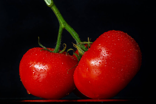 photo tomatoes with drops of water on a black background. - Photo, Image
