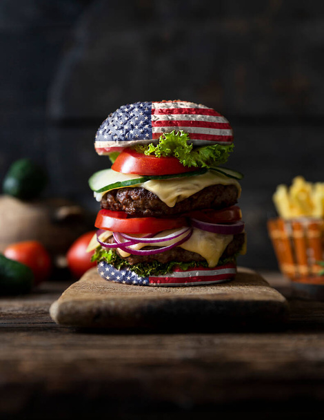 American Burger with tomatoes, onions, cucumber, lettuce and melting cheese. United States of America flag. Happy independence day. 4th of July celebration - Valokuva, kuva