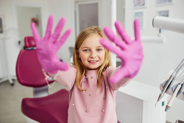 Little girl with gloves on hands standing in stomatology clinic. - Valokuva, kuva