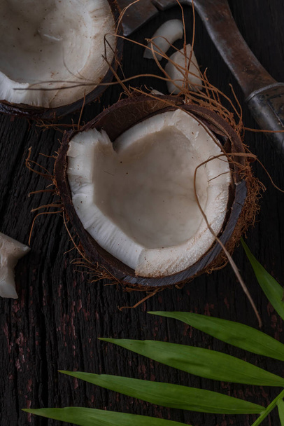 Нарезанный кокос на деревянном фоне, вид сверху. Кокосовое молоко и кокосовые хлопья являются тропической пищей - Фото, изображение