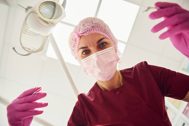 Young female dentist in protective mask working in stomatology clinic. First person view. - Foto, Bild