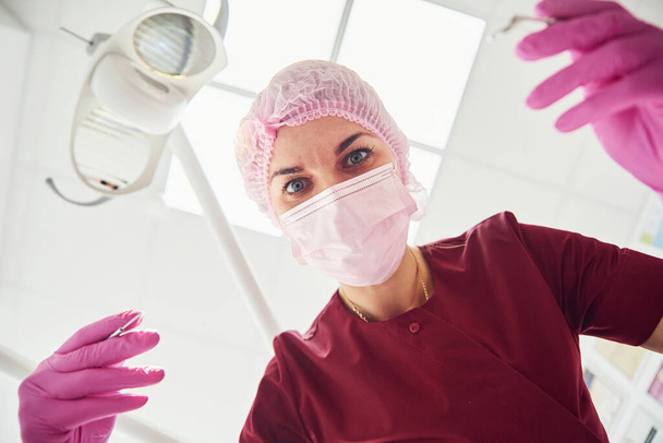 Young female dentist in protective mask working in stomatology clinic. First person view. - Foto, Imagem