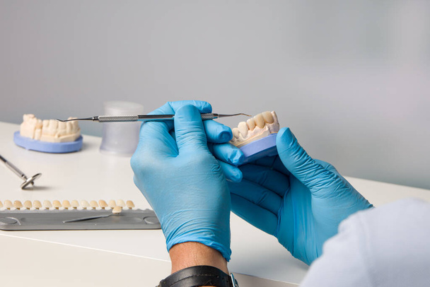 close-up of dental technician working with a brush on tooth crown in dental laboratory - Fotó, kép