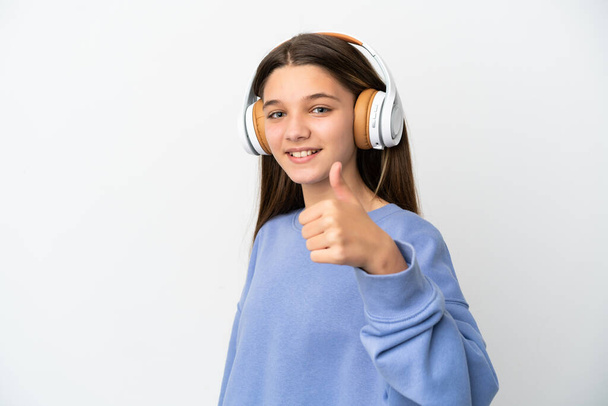Little girl over isolated white background listening music and with thumb up - Fotoğraf, Görsel