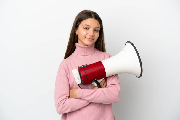 Little girl over isolated white background holding a megaphone and smiling - Photo, Image
