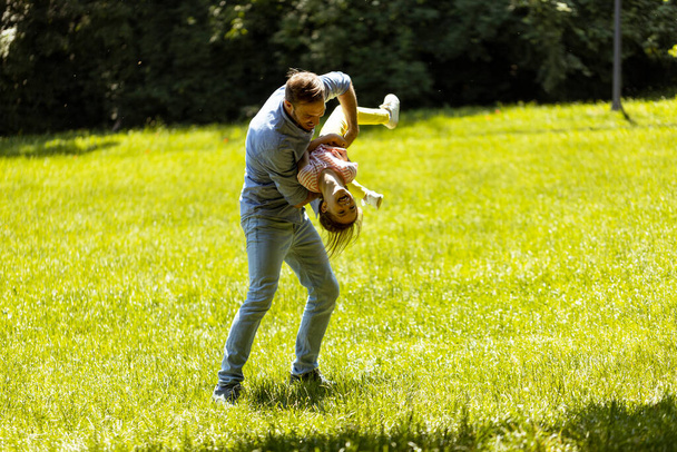 Otec s roztomilou dceruškou baví na trávě v parku - Fotografie, Obrázek