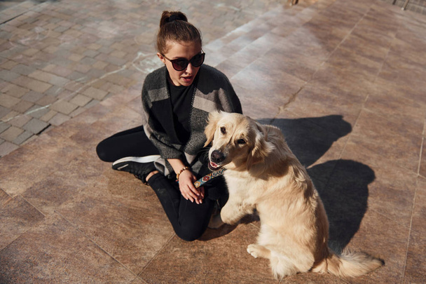 Młoda pozytywna kobieta bawi się ze swoim psem podczas spaceru na świeżym powietrzu. - Zdjęcie, obraz