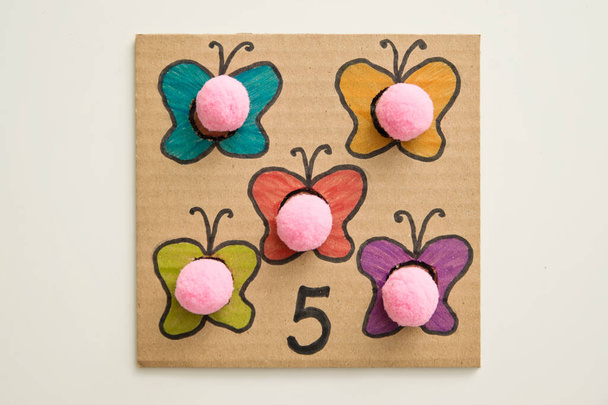 Hand made children home activity from cardboard and pom poms. Early education, Montessori methodology. Implement to develop fine motoric skills, logical thinking learn counting. - Fotó, kép