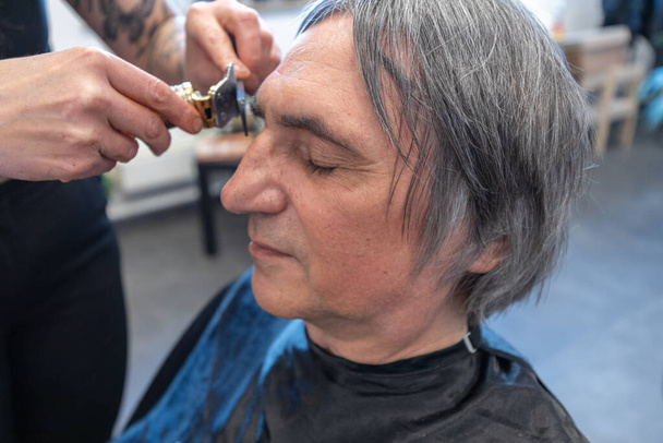 Senior ottiene sopracciglia fatto in un salone di parrucchiere - Foto, immagini