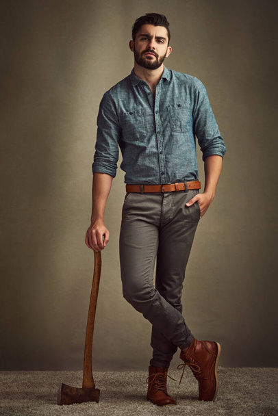 Dashing and daring. Studio shot of a young man posing with an axe against a green background. - Foto, Imagem