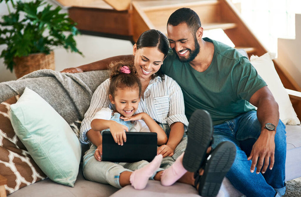 Partage dans la connexion la plus mignonne. Tournage d'une famille heureuse utilisant une tablette numérique ensemble à la maison. - Photo, image