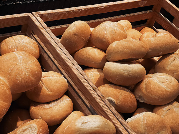 Frische Brotlaibe und Semmeln in rustikaler Backstube, Backwaren vor rustikalem Hintergrund und Bauernmarkt-Konzept - Foto, Bild