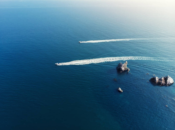 Aerial drone pov widok z góry dwa wybrzeża straży granicznej statków pływających szybko w czystym błękitnym oceanie lub wodzie morskiej na jasny słoneczny dzień. Powyżej pary widok motorówka w pobliżu wysp skalnych malownicze tło morskie - Zdjęcie, obraz