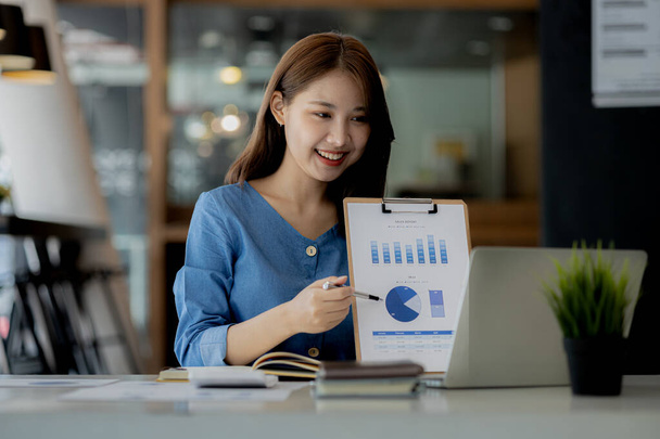 Azjatka pracująca w biurze i dyskutująca z partnerem biznesowym poprzez wideo na laptopie, młoda azjatycka kobieta biznesu jest dyrektorem biznesowym, założycielką startupu. Koncepcja przedsiębiorstwa typu start-up. - Zdjęcie, obraz