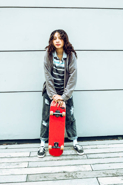 young woman with skateboard in the street having fun smiling, isolated color background - Φωτογραφία, εικόνα