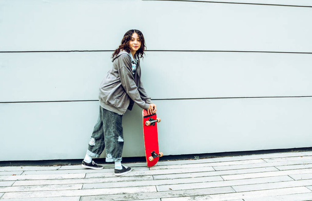 young woman with skateboard in the street having fun smiling, isolated color background - Foto, Imagen
