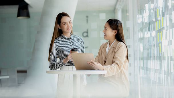 Two women looking at information on their laptops, two business women discussing brainstorming and implementation plans, form a partnership to form a startup. Management concept of startup company. - Photo, Image