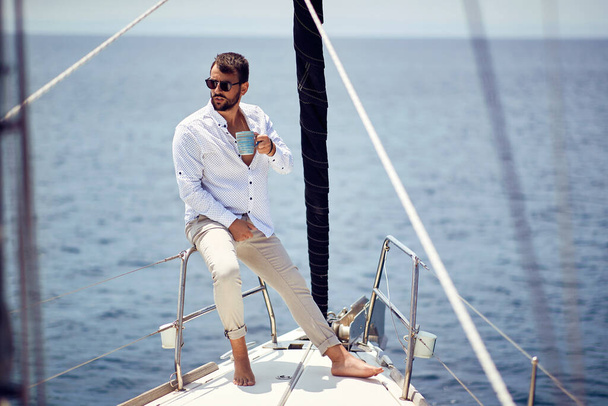 Casual attractive man sailing alone on the yacht; Luxurious lifestyle concept - Foto, immagini