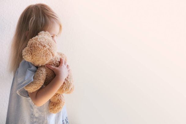 little child, blonde girl 3 years old plays with toy, hugs teddy bear, happy childhood, first impressions, tells plush friend about grudges, complains about domestic violence - Foto, afbeelding