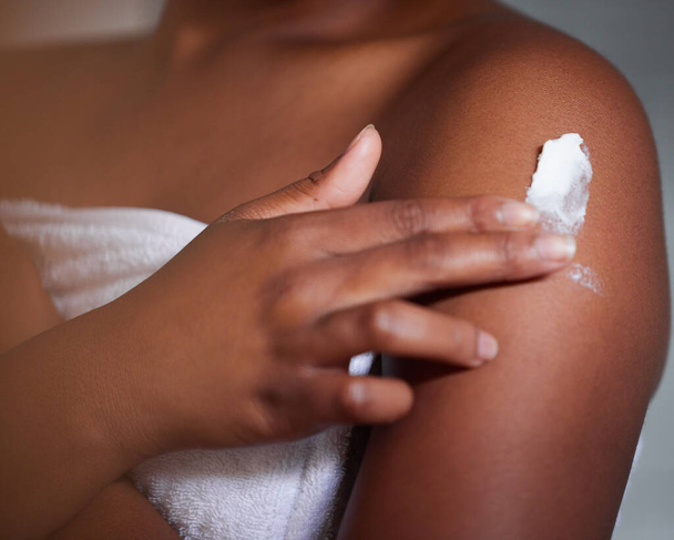 Отсутствие влаги является первым шагом к повреждению кожи. Снимок женщины, применяющей лосьон к телу. - Фото, изображение