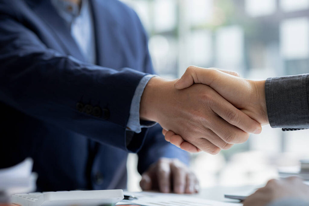 Close-up two business men holding hands, Two businessmen are agreeing on business together and shaking hands after a successful negotiation. Handshaking is a Western greeting or congratulation. - 写真・画像