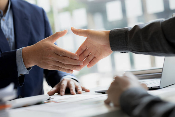 Κοντινό πλάνο δύο επιχειρηματίες κρατώντας το χέρι, Δύο επιχειρηματίες συμφωνούν για τις επιχειρήσεις μαζί και χειραψία μετά από μια επιτυχημένη διαπραγμάτευση. Χειραψία είναι ένας δυτικός χαιρετισμός ή συγχαρητήρια. - Φωτογραφία, εικόνα