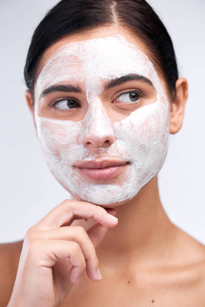 Erstellen Sie eine Routine, die sich gut anfühlt. Studioaufnahme einer jungen Frau mit Gesichtsmaske vor weißem Hintergrund. - Foto, Bild
