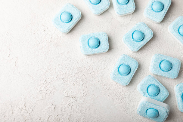 Water softening tablets on a gray texture background. Capsules for washing machines and dishwashers that prevent limescale. Place to copy. - Fotoğraf, Görsel