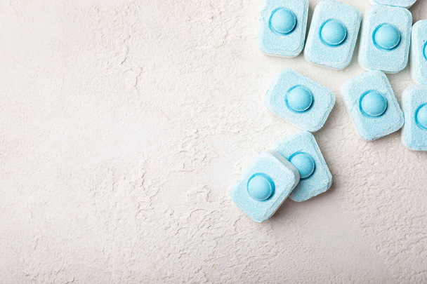 Water softening tablets on a gray texture background. Capsules for washing machines and dishwashers that prevent limescale. Place to copy. - Foto, immagini