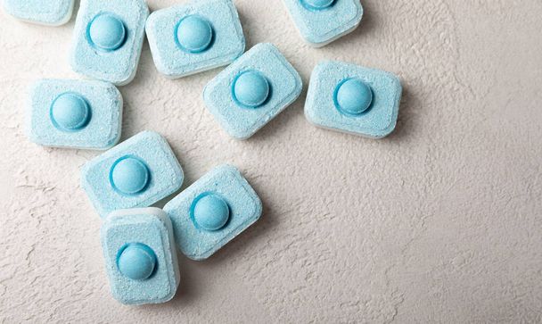 Water softening tablets on a gray texture background. Capsules for washing machines and dishwashers that prevent limescale. Place to copy. - Фото, зображення