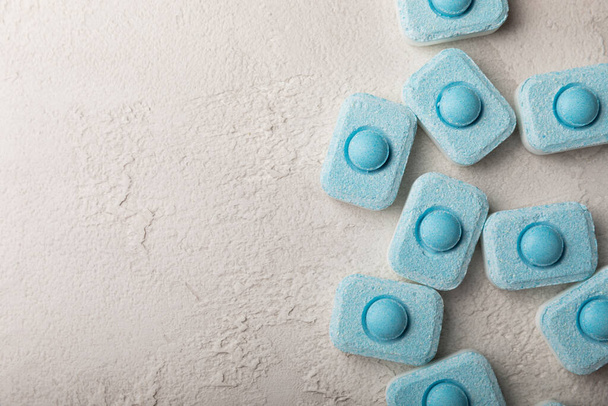 Water softening tablets on a gray texture background. Capsules for washing machines and dishwashers that prevent limescale. Place to copy. - Fotografie, Obrázek