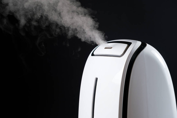 Humidifier with steam jet on a black background. Humidity in the room, maintaining the microclimate in the apartment. - Фото, изображение