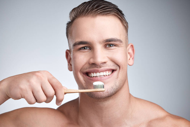 Mundhygiene ist ein Muss. Studioporträt eines attraktiven jungen Mannes beim Zähneputzen vor grauem Hintergrund. - Foto, Bild