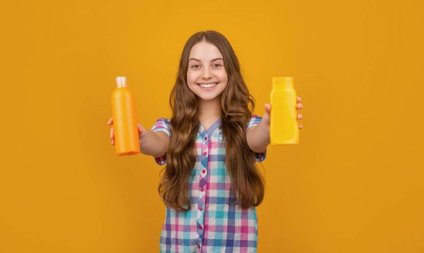 cheerful child with hair conditioner bottle on yellow background - Fotó, kép