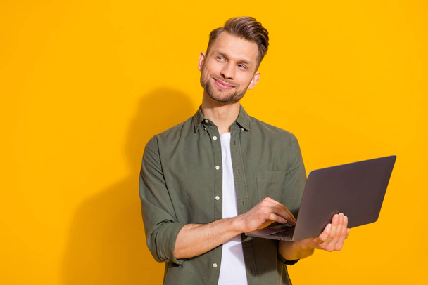 Portrait of attractive minded smart clever cheerful guy using laptop thinking copy space isolated over bright yellow color background - Фото, изображение