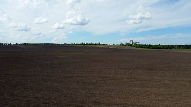 Aerial drone view flight over huge plowed field and blue sky. Skyline, horizon - Photo, Image