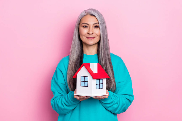 Photo of satisfied lady hold small house look camera isolated on pink color background - Foto, immagini
