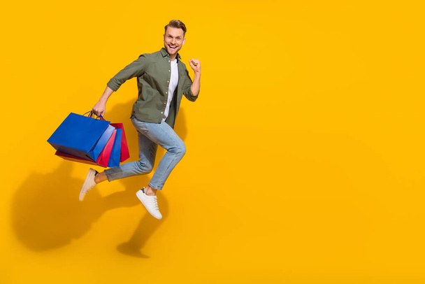 Full length body size view of attractive lucky guy jumping carrying things running copy space isolated over bright yellow color background - Foto, imagen