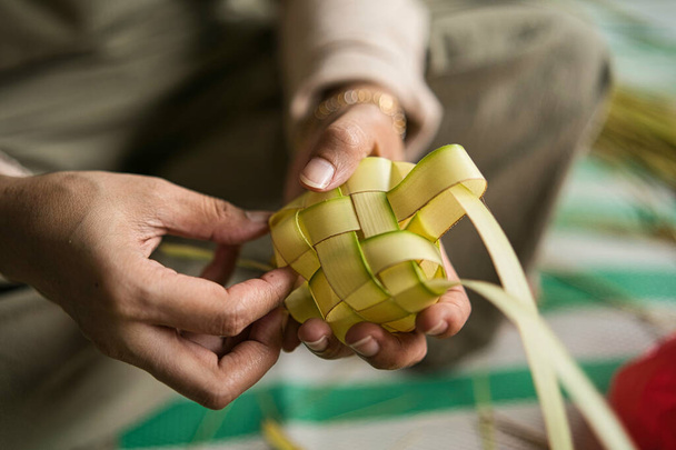 Tessitura delle foglie di cocco fare il ketupat, una cucina tradizionale malese durante la celebrazione Eid. Punti focali selettivi - Foto, immagini