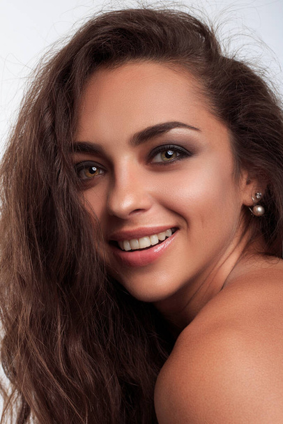 Close up portrait of smily young indian woman with long curly brown hairstyle looking at camera on the white background in photo studio - Φωτογραφία, εικόνα