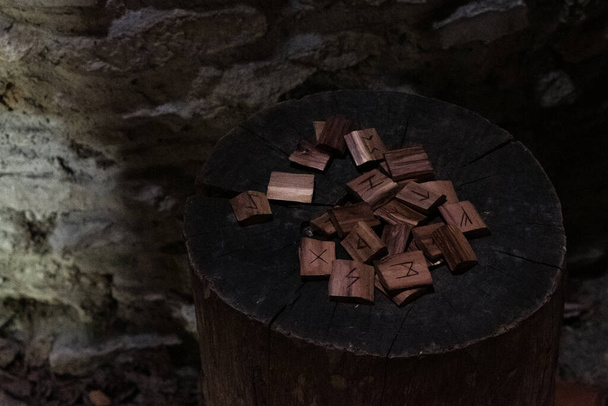 Velhas runas de madeira no cenário medieval escuro. Pilha de lascas de madeira com diferentes símbolos usados para prever o futuro e obter sabedoria. - Foto, Imagem