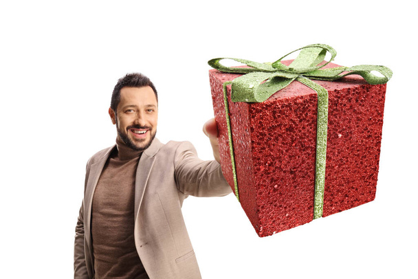 Young man holding a glittery red present box isolated on white background - Фото, изображение