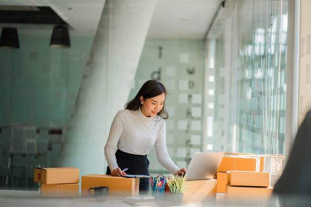 Start a small business, independent SME entrepreneur, portrait of Asian woman working from home, box, smartphone, laptop, online, marketing, packaging, shipping, parcel SME, eCommerce concept. - Fotoğraf, Görsel