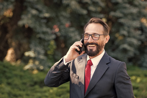 Portrait of happy professional in suit talking on cell phone outdoor in green park. Business lifes concept - Фото, зображення