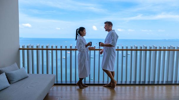 couple men and woman having a coffee on the balcony looking out over the bay of Pattaya, Thai girl and European man on balcony of apartment condo in Thailand - Foto, Imagen