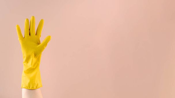 Hand in yellow rubber glove shows OK gesture with fingers on beige background. Copy space - Valokuva, kuva