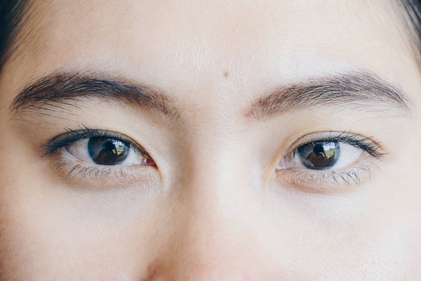 Close up shot of young Asian woman face, open her eyes and looking to the camera. - Фото, зображення