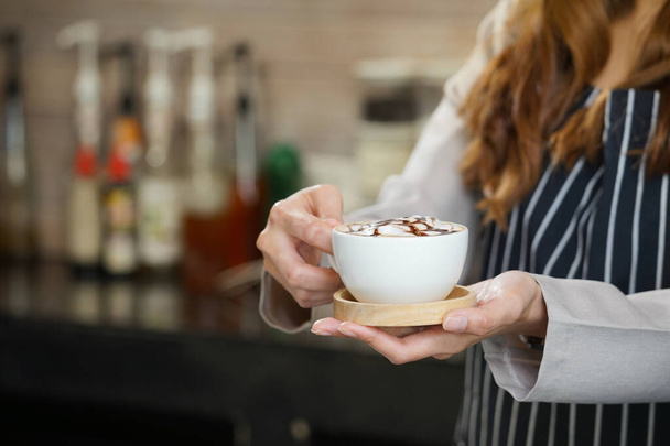 waitress is serving a cup of hot coffee in cafe                               - Foto, afbeelding