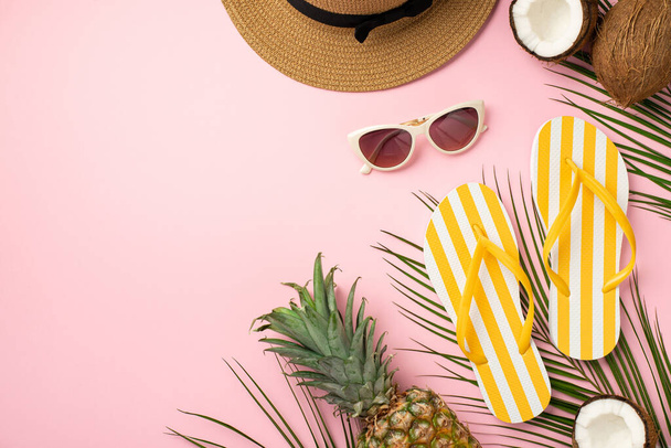 Concepto de fin de semana. Vista superior de la foto del sombrero de sol amarillo rayas chanclas gafas de sol cocos piña y hojas de palma sobre fondo rosa pastel aislado con copyspace - Foto, imagen